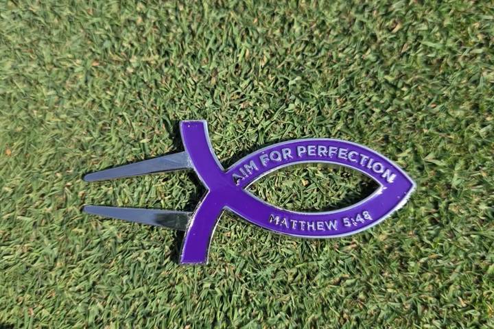Purple Aim for Perfection divot tool on the green