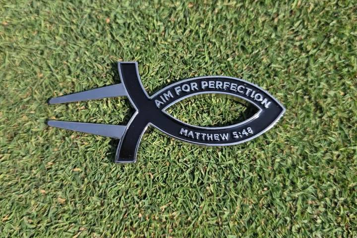 Black Aim for Perfection divot tool on the green
