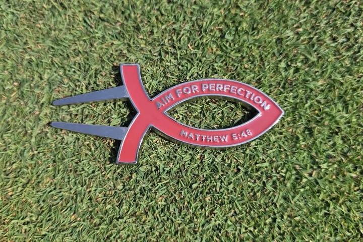 Burgundy Aim for Perfection divot tool on the green