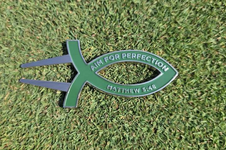 Green Aim for Perfection divot tool on the green
