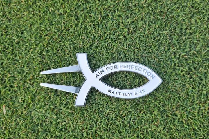 White Aim for Perfection divot tool on the green